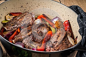 Roasted slow cooked lamb shanks with vegetables and herbs. Wooden background. Top view