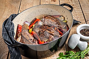 Roasted slow cooked lamb shanks with vegetables and herbs. Wooden background. Top view