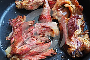 Roasted smoked pork shoulder or knee. Delicious meat on a black baking sheet with drops of vegetable oil, taken out of