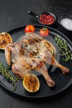 Roasted spatchcock poussin, on black background