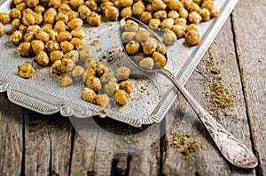 Roasted spicy chickpeas with zaatar or zatar on vintage metall try and wooden background. Top view