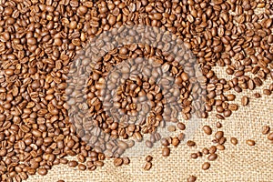 Roasted spilled coffee beans on sackcloth background