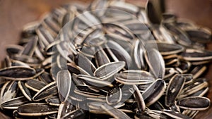 Roasted sunflower seeds falling into a rustic wooden bowl in slow motion