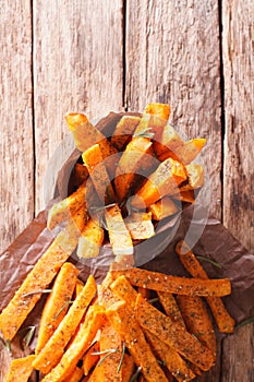 Roasted sweet potatoes with herbs in a paper cone close-up. vert