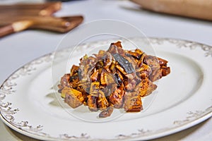Roasted Sweet Potatoes on Ornate Plate with Rustic Kitchen Backdrop