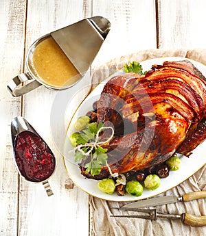 Roasted turkey with bacon and garnished with chestnuts and brussels sprouts.