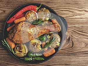 Roasted turkey leg with vegetables, carrots, peppers, potatoes vegetables in frying pan