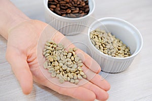 Roasted and unroasted coffee in bowls. Green coffee beans on the palm closeup