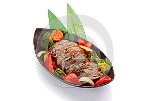 Roasted veal with vegetables on a black plate isolated