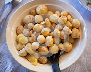 Roasted whole baby potatoes with greens and garlic oil over white background