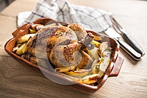 Roasted whole chicken with potatoes in baking dish. Tasty food a