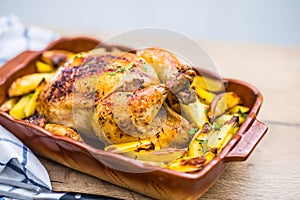 Roasted whole chicken with potatoes in baking dish. Tasty food at home on the kitchen counter