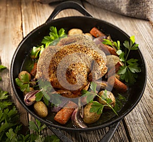 Roasted whole chicken with vegetables in a cast iron pan