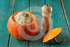 Roasted whole pumpkin with rice and meat with pepper mill