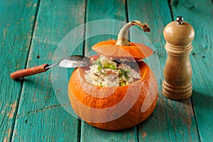 Roasted whole pumpkin with rice and meat with pepper mill