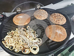 Roasting onions and burger buns on an electric grill