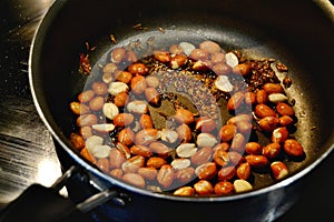 Roasting peanuts and jeera indian cumin on ghee on an electrical ceramic stovetop