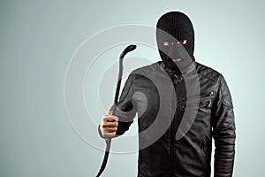 Robber, bandit in a balaclava with a crowbar in his hands on a light background. Robbery, hacker, crime, theft. Copy space