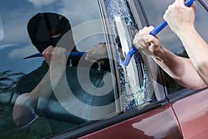 Robber with crowbar smashing glass