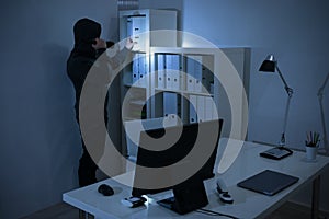 Robber With Flashlight Searching For Documents In Office