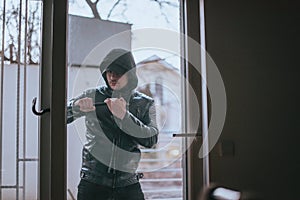 Robber in hood breake glass window