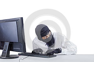 Robber with mask hacking a computer