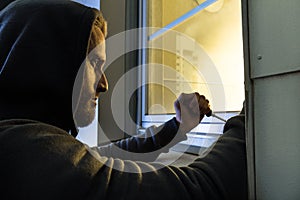 Robber Using The Screwdriver To Open The Glass Window