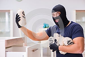 The robber wearing balaclava stealing valuable things