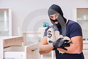 The robber wearing balaclava stealing valuable things