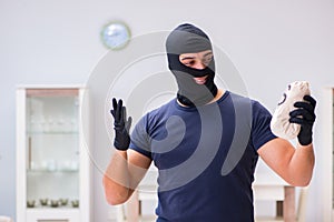 The robber wearing balaclava stealing valuable things