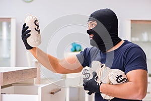 The robber wearing balaclava stealing valuable things