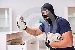 The robber wearing balaclava stealing valuable things