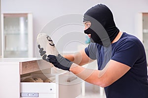 The robber wearing balaclava stealing valuable things