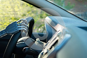 Robot arm on a steering wheel. Artificial intelligence drives a car. Autonomous vehicle concept.