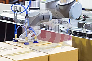 The robot arm transfers carton box  to conveyor line