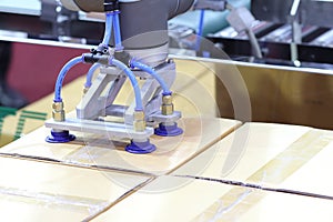 The robot arm transfers carton box  to conveyor line