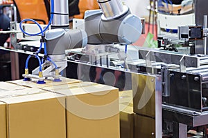 The robot arm transfers carton box  to conveyor line