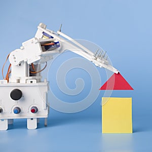 Robot hand building house of wooden blocks