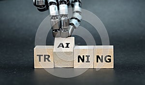 Robot Hand turns wooden cube and puts the letters AI (artificial intelligence) to the word training