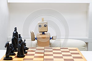 Robot with hands sitting at the table playing a game of chess. A