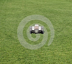 Robot lawn mower mowing in the center of a perfectly cut meadow