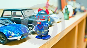 The robot is standing in front of his blue car.