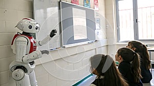 Robot teaching a class of students in front of a whiteboard in school