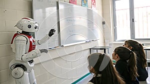 Robot teaching students at a whiteboard in a bright classroom