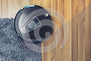 Robot vacuum cleaner cleaning on dusty wooden floor