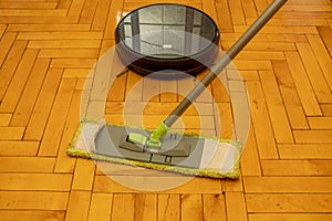 Robot vacuum cleaner on lacquered parquet against a conventional mop.