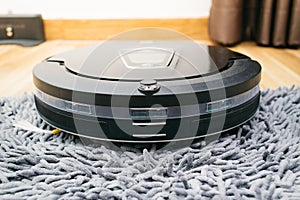Robot vacuum cleaner on laminate wood and carpet.
