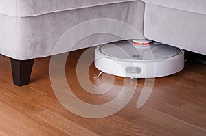 Robot vacuum cleaner runs on wood parquet floor. Modern smart cleaning technology housekeeping