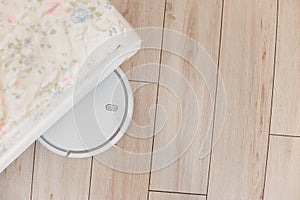 Robot vacuum cleaner vacuuming under the bed. Top view