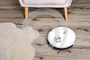 A robot vacuum cleaner on a wooden floor in a modern interior. Selective focus.